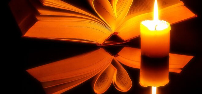 Kirja jonka sivut taitettu sydämeksi ja kynttilä kirjan edessä