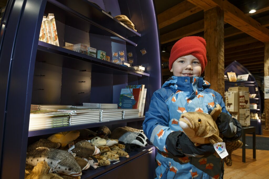Lapsi Riihisaaren museokaupassa pehmokala kädessään.