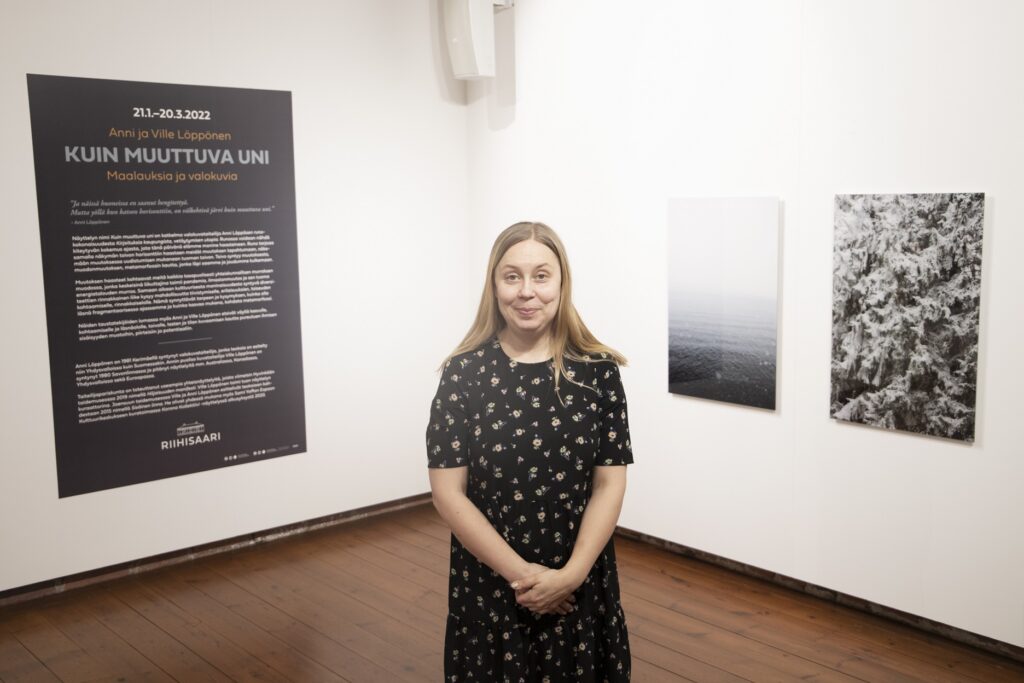 Nainen seisoo taidenäyttelyssä.