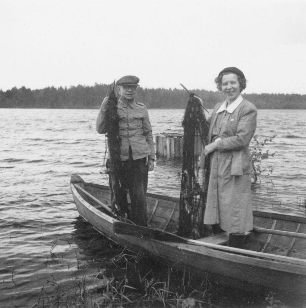 Kaksi ihmistä seisoo veneessä ja pitää käsissään kalaverkkoja.