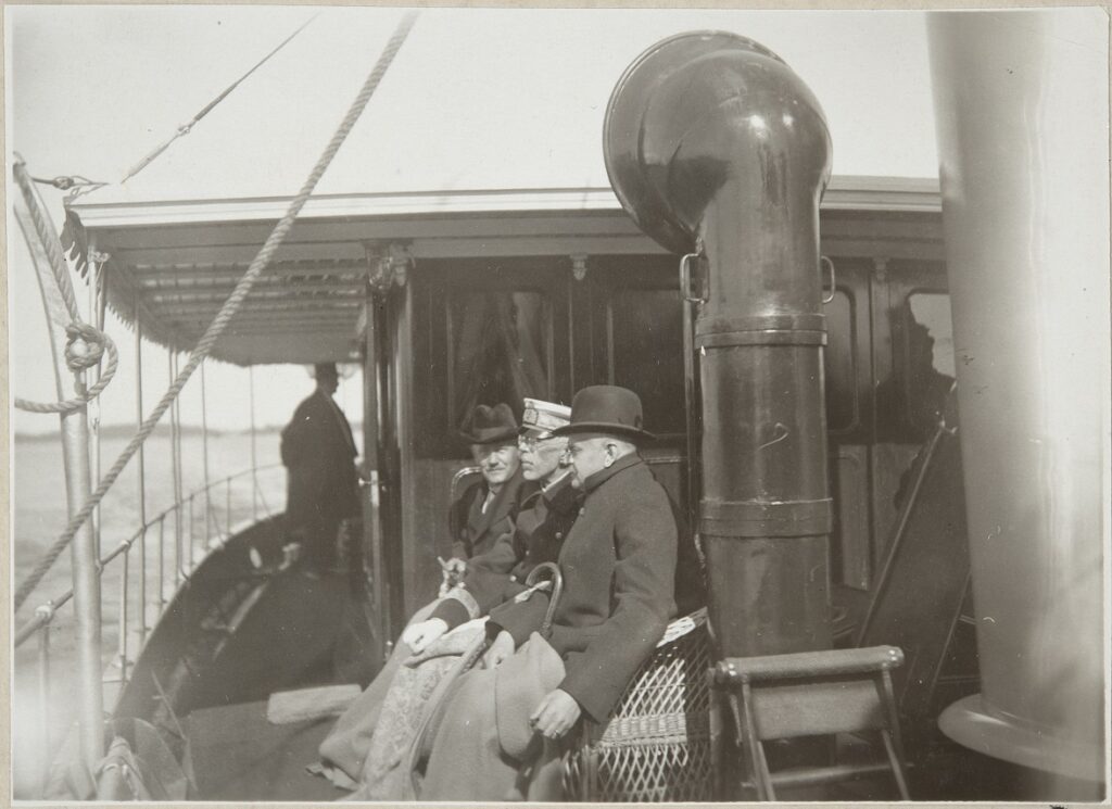 Kolme ihmistä istuu laivan kannella.