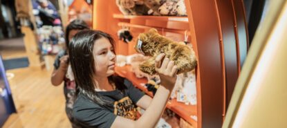 Lapsi katsoo pehmolelua, taustalla hyllyllä muita pehmoleluja.