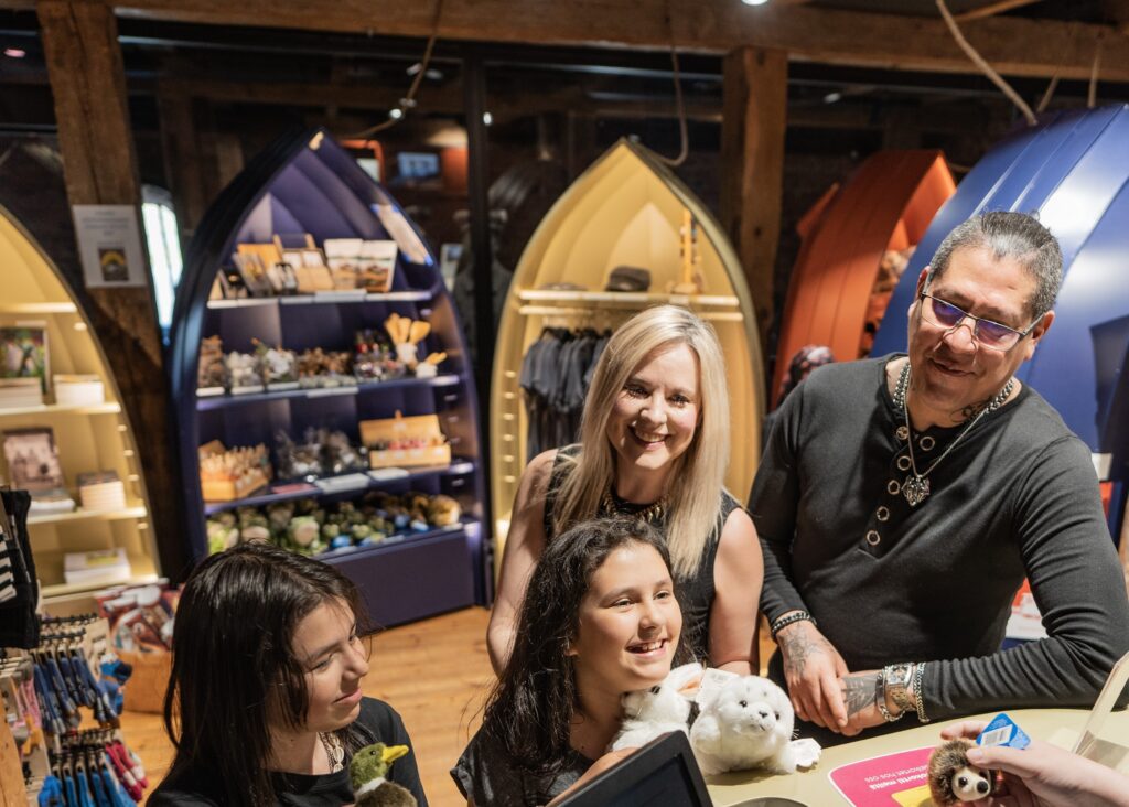 Neljä ihmistä nojailee asiakaspalvelutiskiin ja hymyilee.