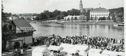 Paljon ihmisiä sekä torikojuja. Taustalla vettä sekä kirkontorni.