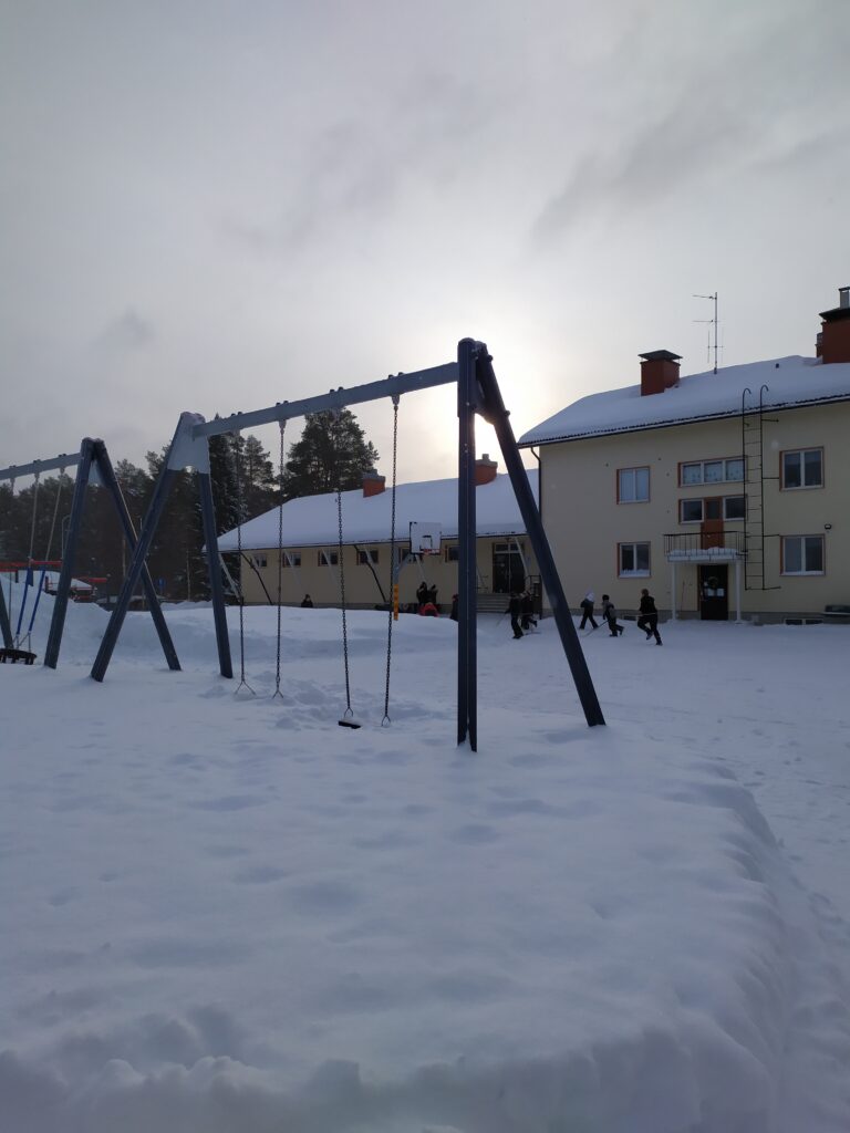 luminen koulun piha talvella, lapsia koulun edustalla leikkimässä