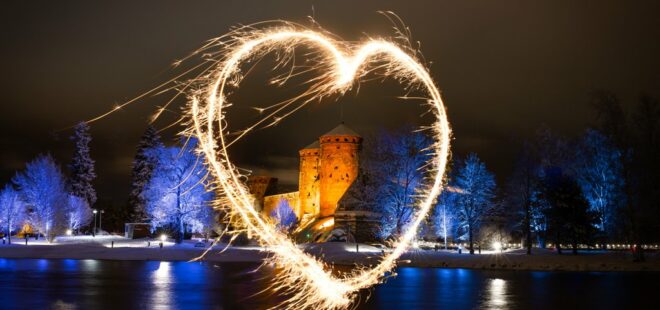 Sydämen muotoinen valokehä ja tumma Olavinlinna taustalla