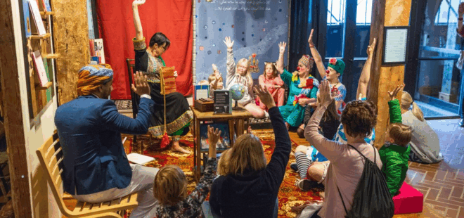 Lapsia ja aikuisia ryhmässä tekemässä taide-esitystä.