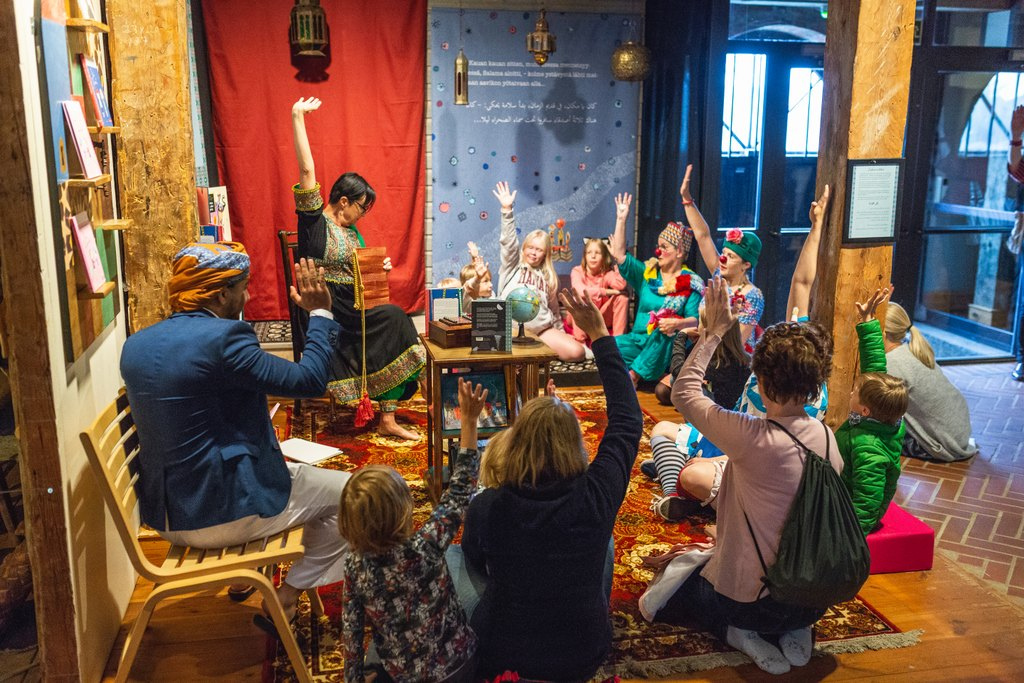 Lapsia ja aikuisia ryhmässä tekemässä taide-esitystä.