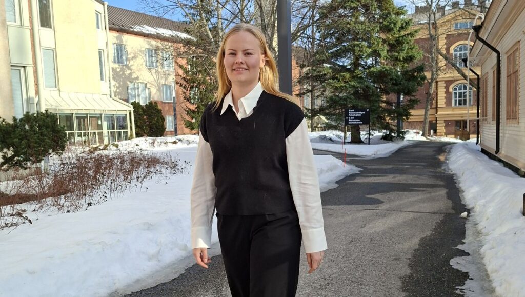 Nuori nainen kävelee ulkona kevätauringossa.