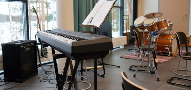 Sähköpiano ja rummut musiikkiluokassa.